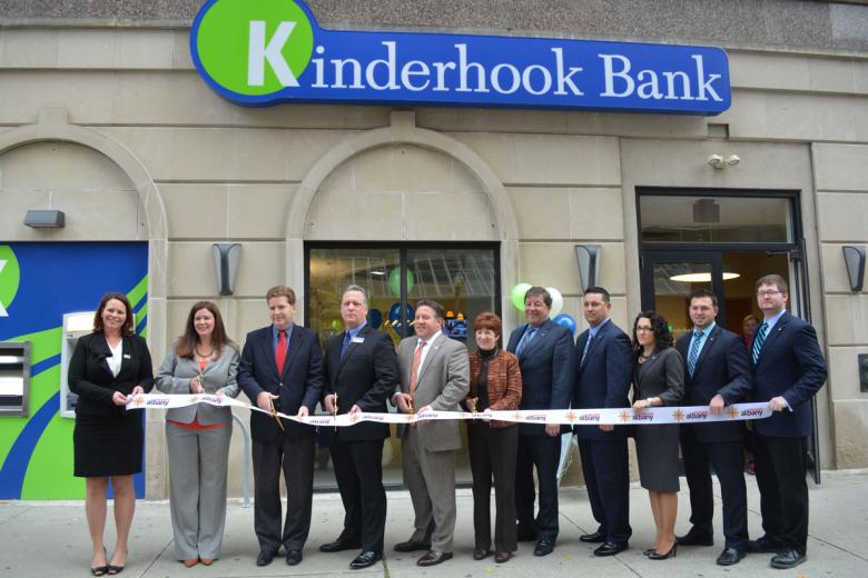 Kinderhook Bank employees and Downtown Albany BID stand in front of the new location holding a ribbon for the grand opening ceremony 