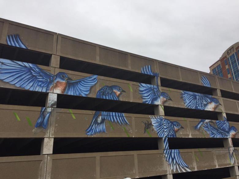 Mural of blue birds painted on the side of a parking garage