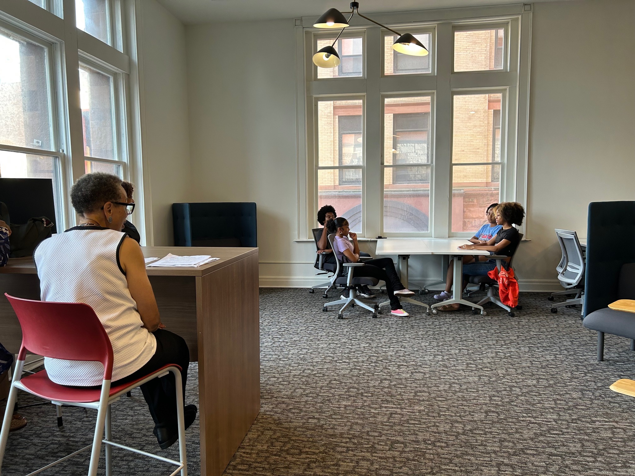 People at foreground and background sit at tables in office space