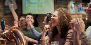 A group of people at a bar watching football and cheering on their team