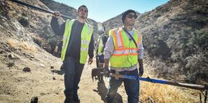 Two men with yellow saftey vests walk in canyon