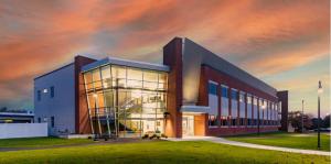 Color rendering of modern brick and glass building lit up at sunset