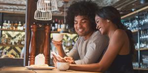 Young urban couple having coffee and using phone app