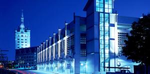 Night photo of glass and metal building lit up with Albany SUNY Admin building in background