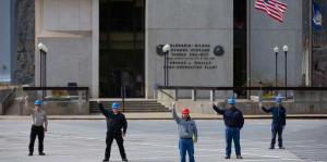 Men in hard hats stand in solidarity in front of building