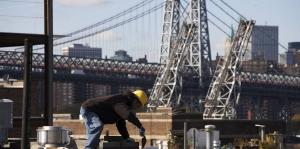 Masonry worker with hard hat and trowel in front of bridge and cityscape