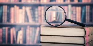 Magnifying glass on stack of books with law books on shelves in background