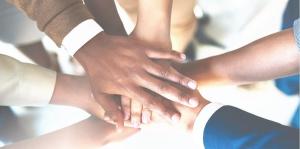 Businesspeople's hands from all races in on top of one another like a team huddle