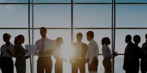 Silhouettes of business people talking in groups in front of sunny window with skyline