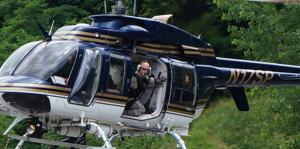 NYS helicopter with Trooper looking down at tree tops