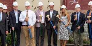 Men and women in hard hats with shovels at groundbreaking