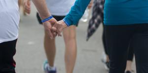 People walking for a cause with blue bracelets on and holding hands