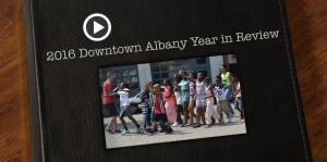 Screenshot of the year in review video superimposed on a leather bound book cover, text above it reads "2016 Downtown Albany Year in Review"