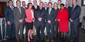 BID board members dressed in fancy business attire stand in front of a step and repeat board, smiling at the camera. 