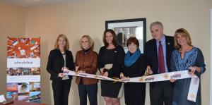 Employees stand with Albany Mayor and BID representatives holding a ribbon for their ribbon cutting ceremony