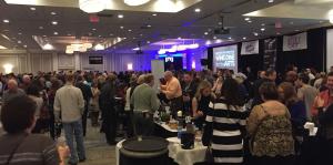 A crowd of patrons at the albany wine and dine for the arts event, networking and holding conversation over food and drink. 