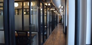 View down a newly renovated hallway, with big lightbulbs and many offices separated by glass 