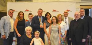 Award recipients stand in front of a step and repeat banner facing the camera and smiling