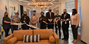 Employees stand with Albany Mayor and BID representatives holding a ribbon for their ribbon cutting ceremony