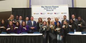 Athletes pose in front of conference tables holding tickets to the event and smiling