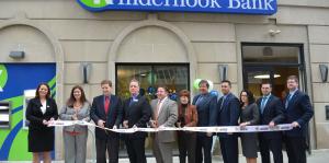 Kinderhook Bank employees and Downtown Albany BID stand in front of the new location holding a ribbon for the grand opening ceremony 