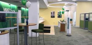 Interior of a newly renovated bank lobby, green balloons celebrate the occasion. 