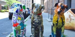 Three nipper dog statues designed and painted in different patterns sit facing the camera