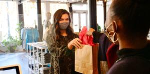 Shopper receiving her purchase in a gift bag over the counter from the employee