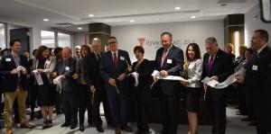 Employees stand with Albany Mayor and BID representatives holding a ribbon for their ribbon cutting ceremony