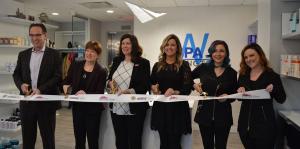 Employees stand with Albany Mayor and BID representatives holding a ribbon for their ribbon cutting ceremony