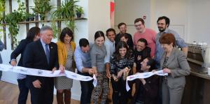 Ribbon cutting in front of a wall of greenery in the new cafe