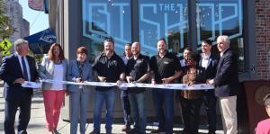 Employees stand with Albany Mayor and BID representatives holding a ribbon for their ribbon cutting ceremony