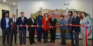 Employees stand with Albany Mayor and BID representatives holding a ribbon for their ribbon cutting ceremony