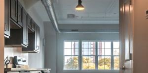 The Lofts apartment interior shot looking down a hallway at large windows and a wide open living space