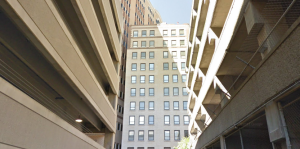 Narrow view down a side street, multi-level parking garages on either side of the street 