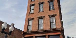 Exterior facade of a brownstone with the African American Cultural Center logo on the street level space