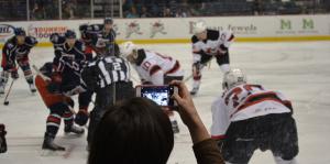 Fan takes a photo on their cell phone during an Albany Devils hockey game