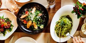 Overhead image of a group of dishes on a table, some plates are empty while some have meals like vegetable stir fry and pesto 