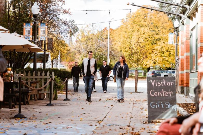 People walking in Quackenbush Square with fall foliage trees 