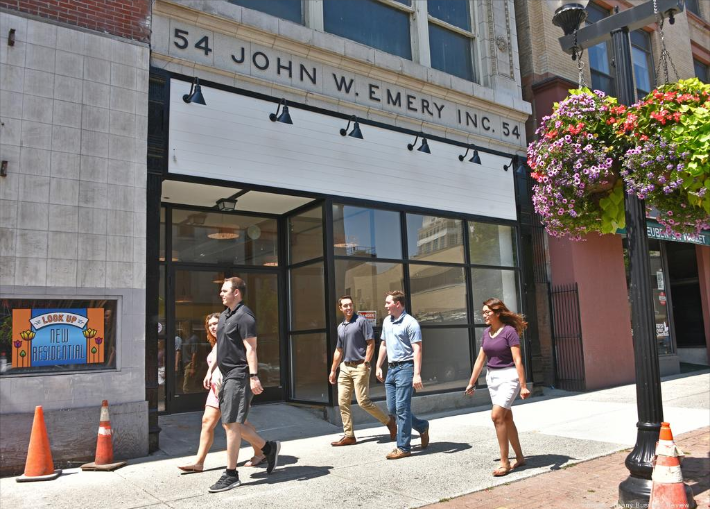 Five pedestrians walk in front of a vacant building that is set to be the new location for Steuben Street Market