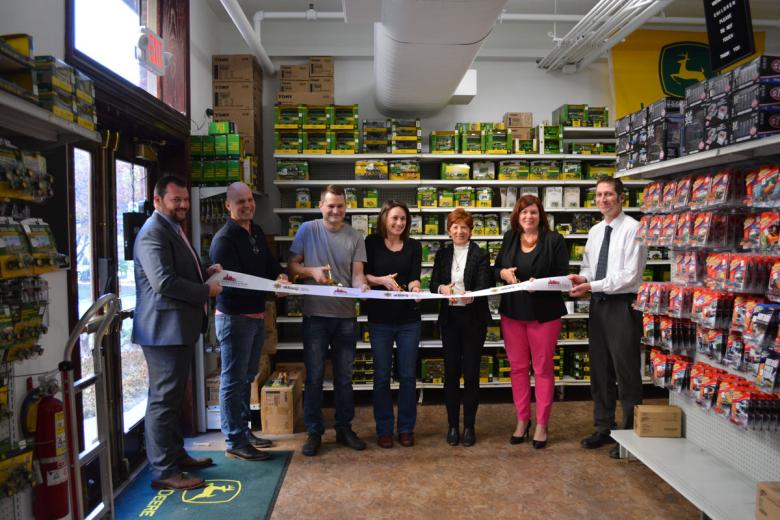 Employees stand with Albany Mayor and BID representatives holding a ribbon for their ribbon cutting ceremony