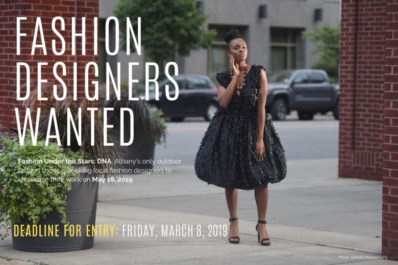 Model in a short black dress stands between brick pillars, text on the left of the image reads "Fashion Designers Wanted"