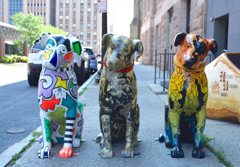 Three nipper dog statues designed and painted in different patterns sit facing the camera