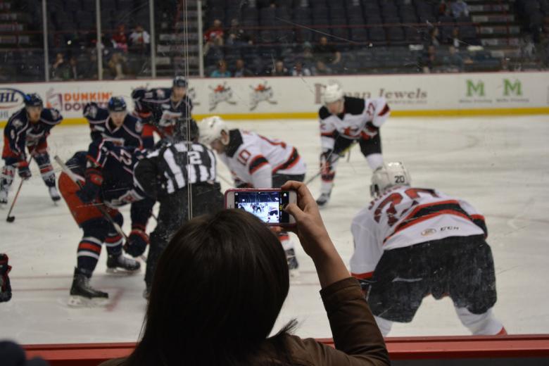 Fan takes a photo on their cell phone during an Albany Devils hockey game